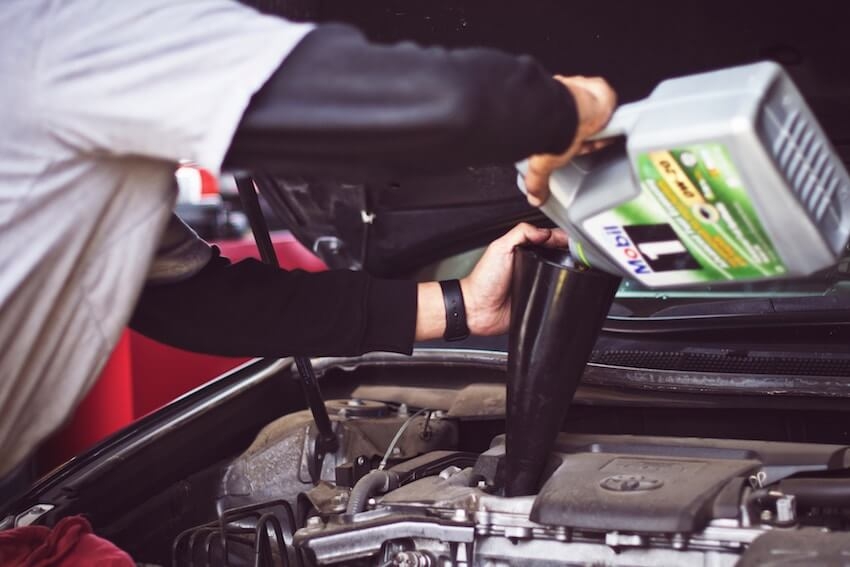 oil being poured into an engine in a garage